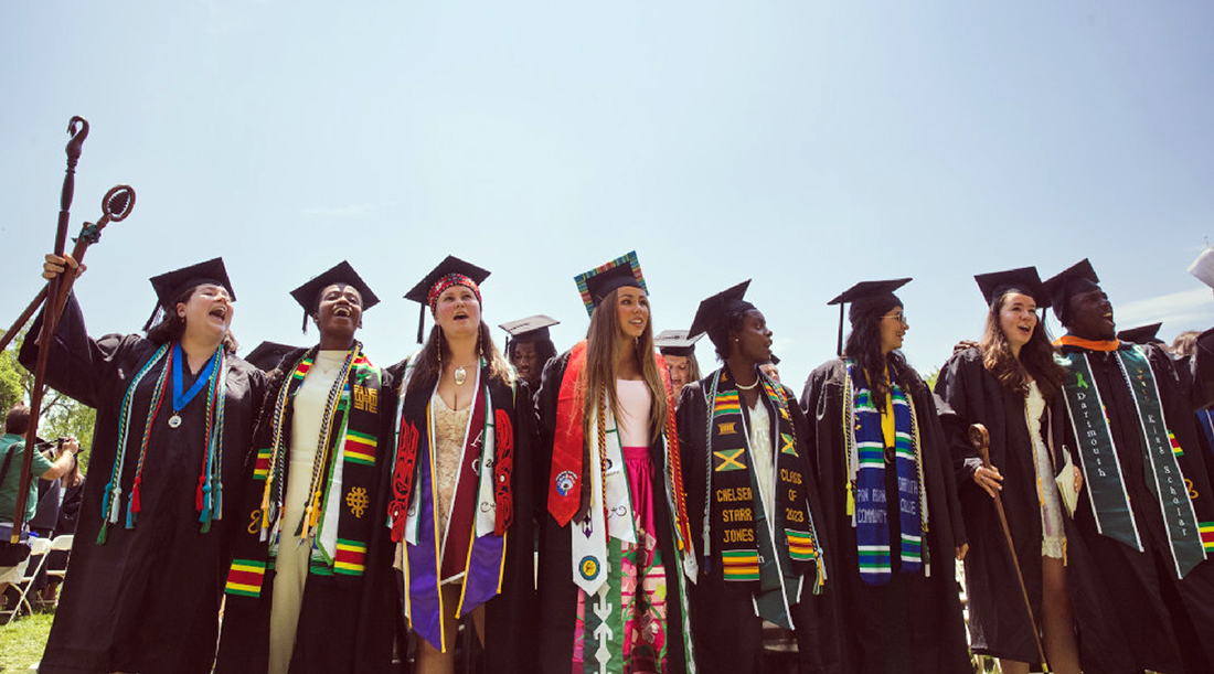 A group of eight students in regalia celebrate at Dartmouth commencement