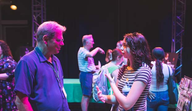 A man in blue shirt and a women in striped shirt talking to each other. 