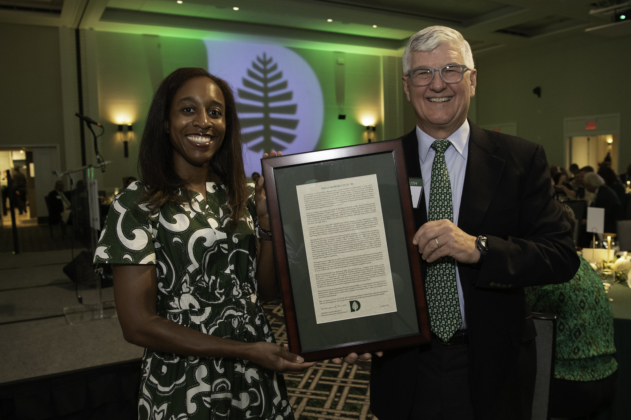 Alumni council president Alex Barnett holding an award with Bill Burgess