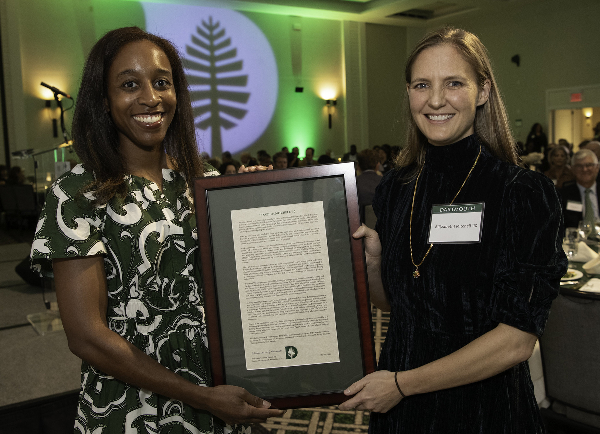 Alumni council president Alex Barnett holding an award with Elizabeth Mitchell