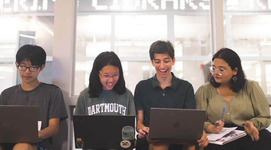 Four seated students working on their computers  