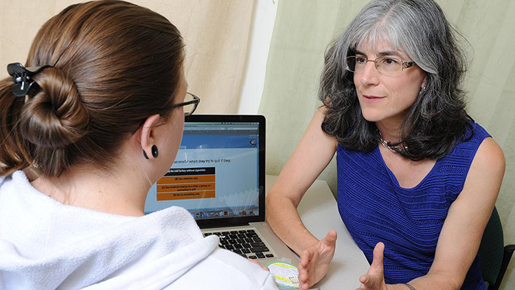 Doctor speaking with patient in an office with a computer open