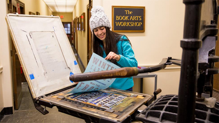 A student in the library creating a Winter Carnival poster