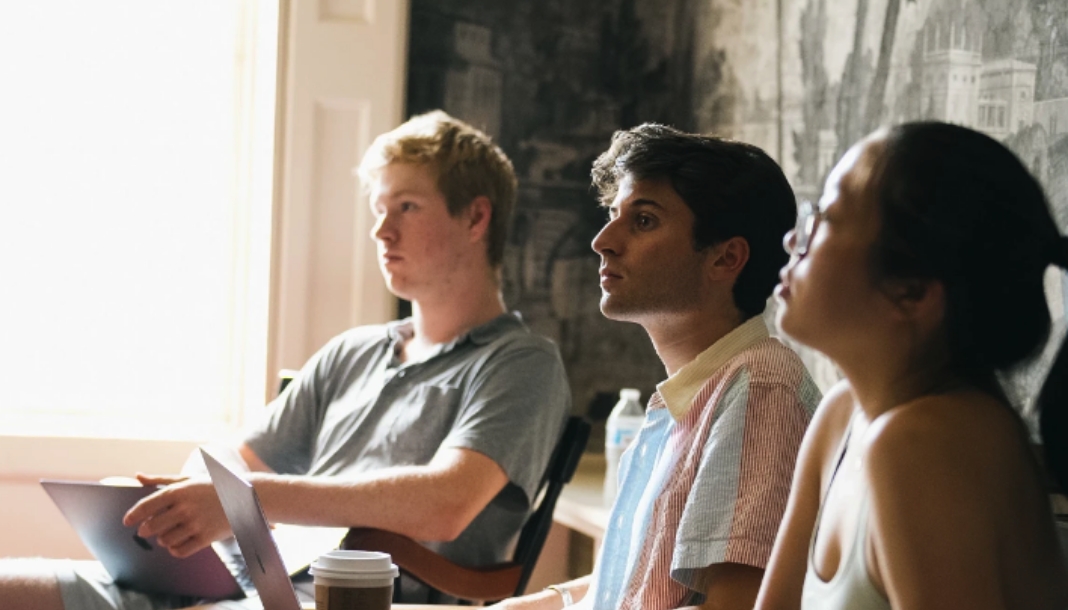 Three students listening to a lecture in a classroom. 