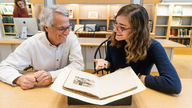 A faculty member and a student in Rauner Library study an old manuscript