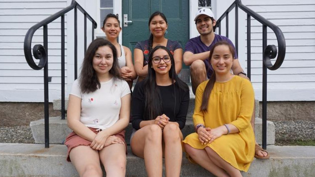 A group of six Dartmouth community members sit outside a building on campus