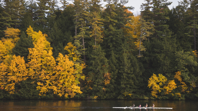 The Connecticut River with autumn trees and a crew boat on the water. 