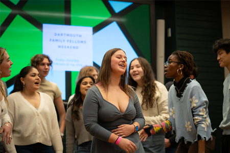 A girl singing a solo in an a cappella performance with students in a semicircle behind